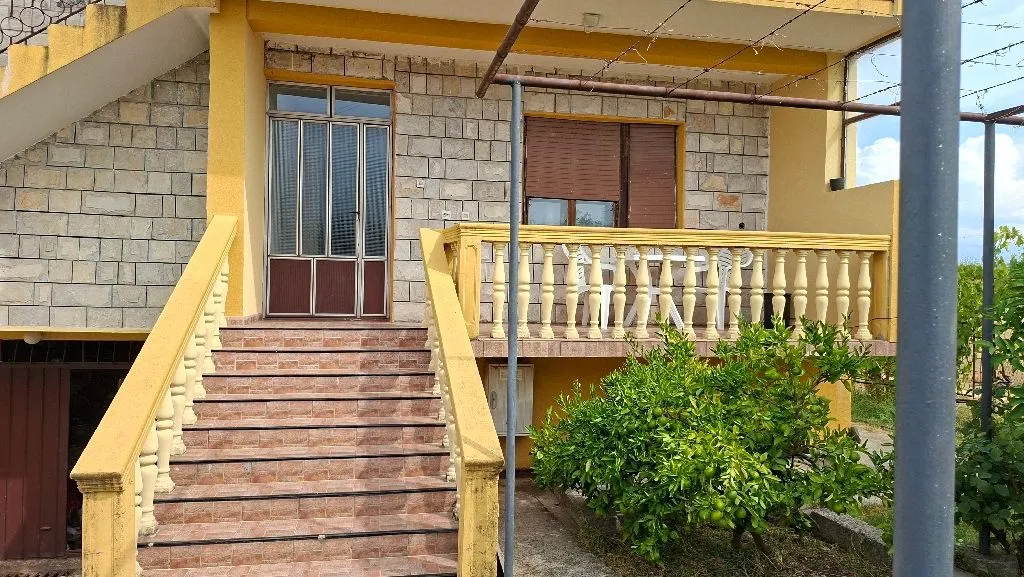 Eksterijer kuće sa spoljnim stepeništem, ulazom i terasom.