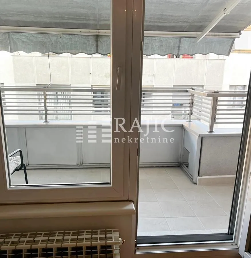 View of a spacious balcony with a railing through balcony doors.