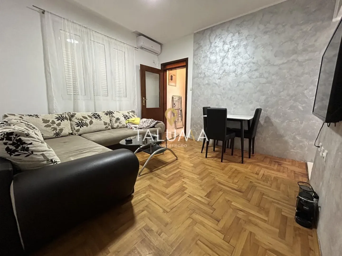 Living room with a sofa set, dining table and parquet flooring.