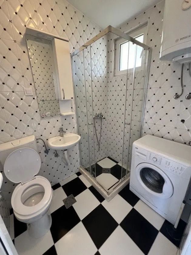Kompaktno kupatilo sa tuš kabinom, umivaonikom, wc šoljom i veš mašinom.