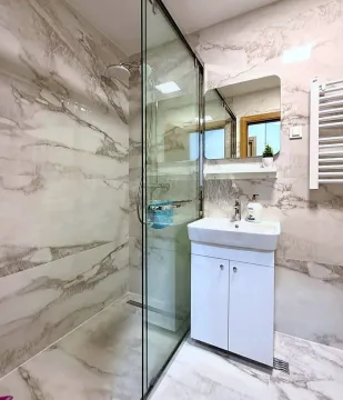 Modern bathroom featuring a glass-enclosed shower and a vanity sink. - image 11