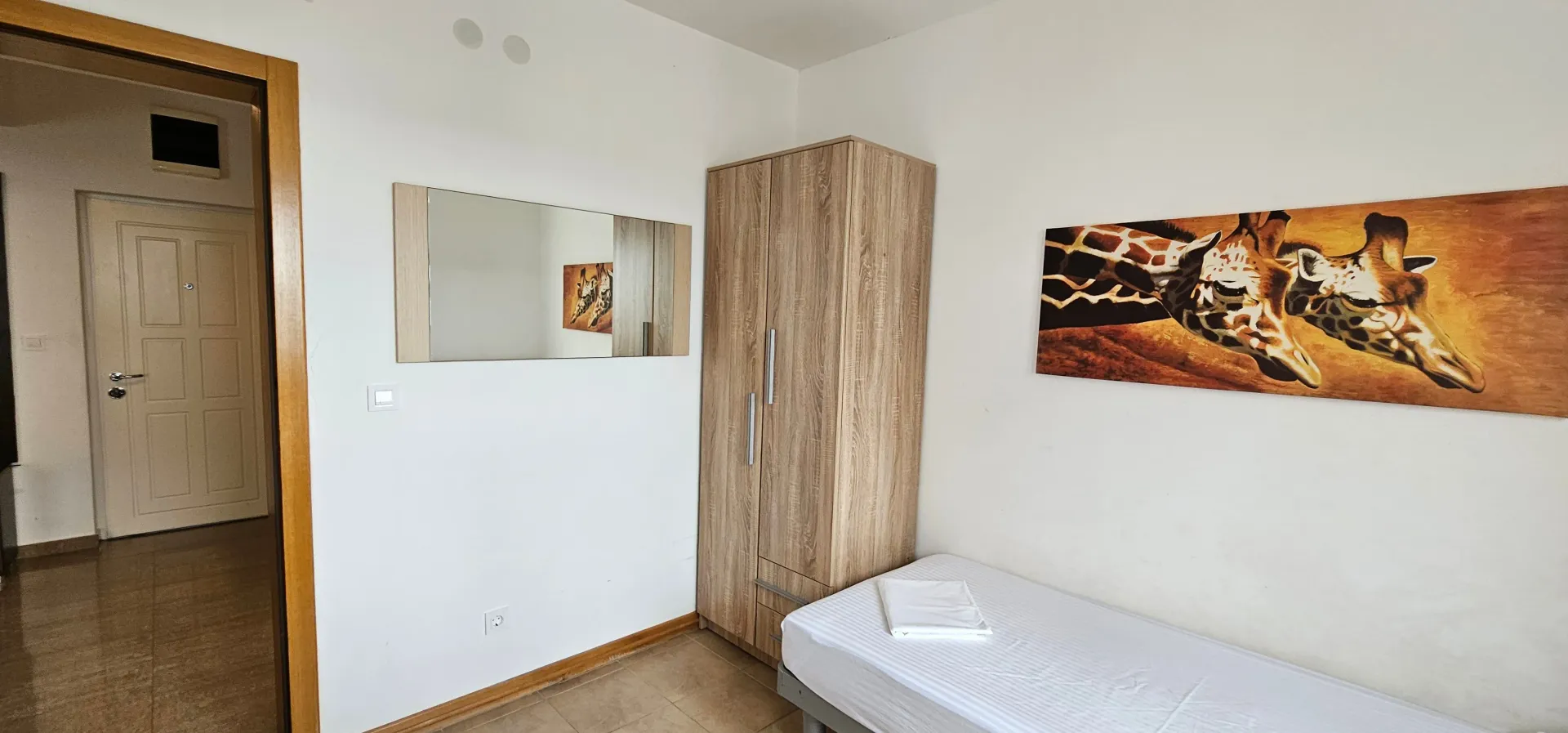 Namještena spavaća soba sa krevetom, garderoberom i slikom na zidu.