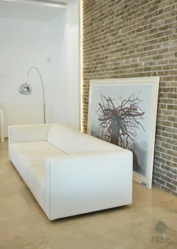 Bijela kožna sofa u dnevnoj sobi sa zidom od opeke i umjetničkom slikom. - image 8
