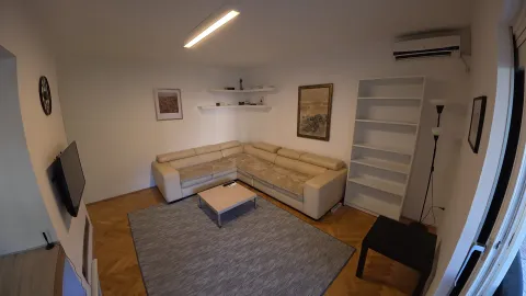 Living room with a corner sofa, shelves, and a TV. - image 12