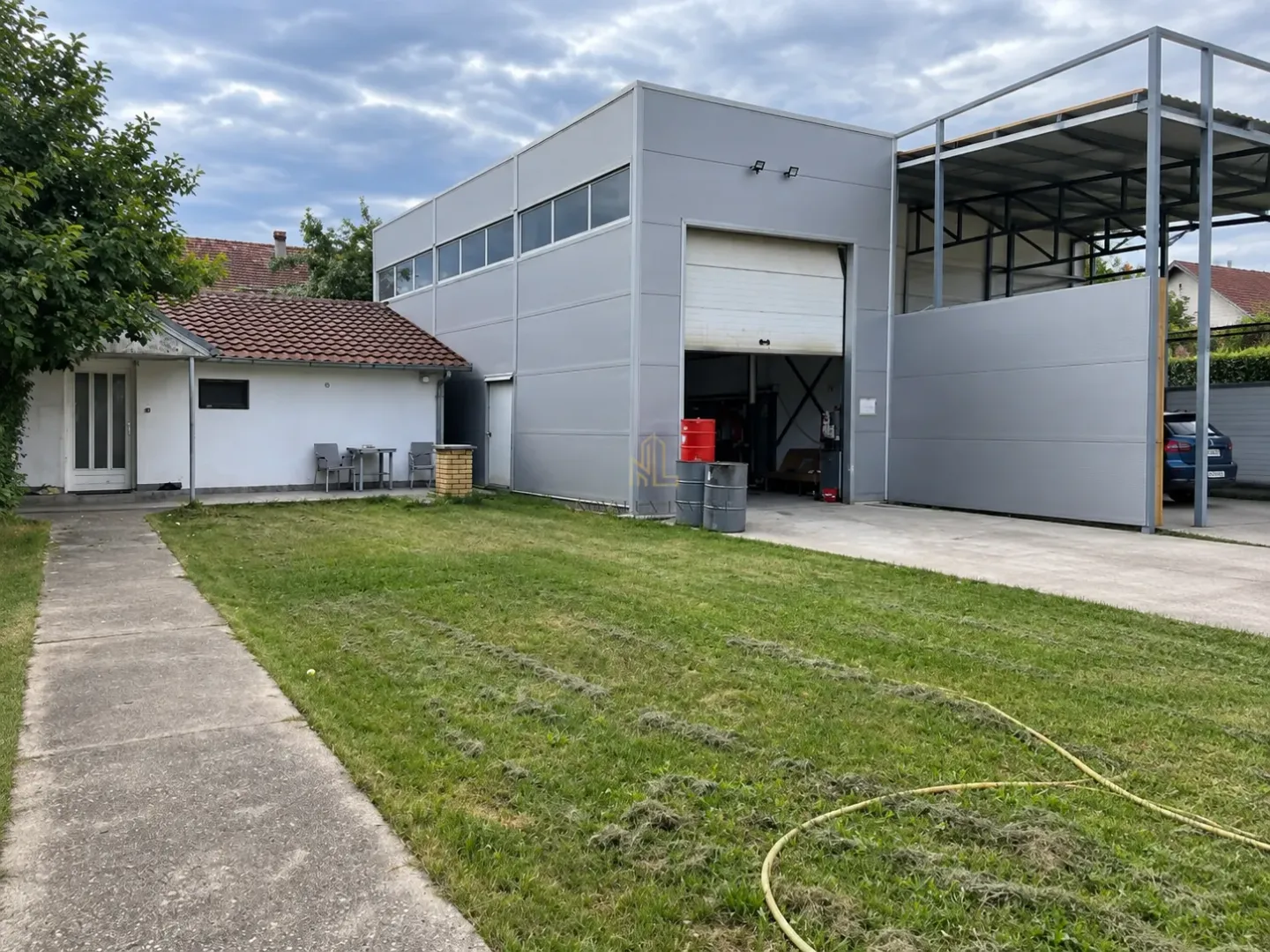 View of the yard with a lawn, a smaller house, and an auxiliary industrial building.