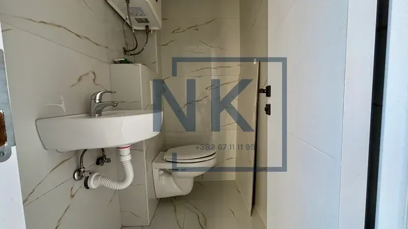 Small bathroom tiled with ceramic tiles featuring a sink and a toilet bowl.