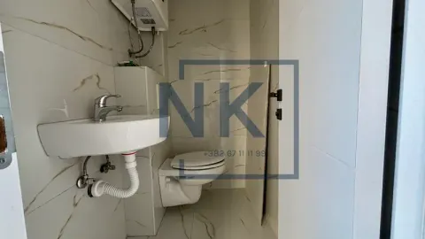 Small bathroom tiled with ceramic tiles featuring a sink and a toilet bowl. - image 5