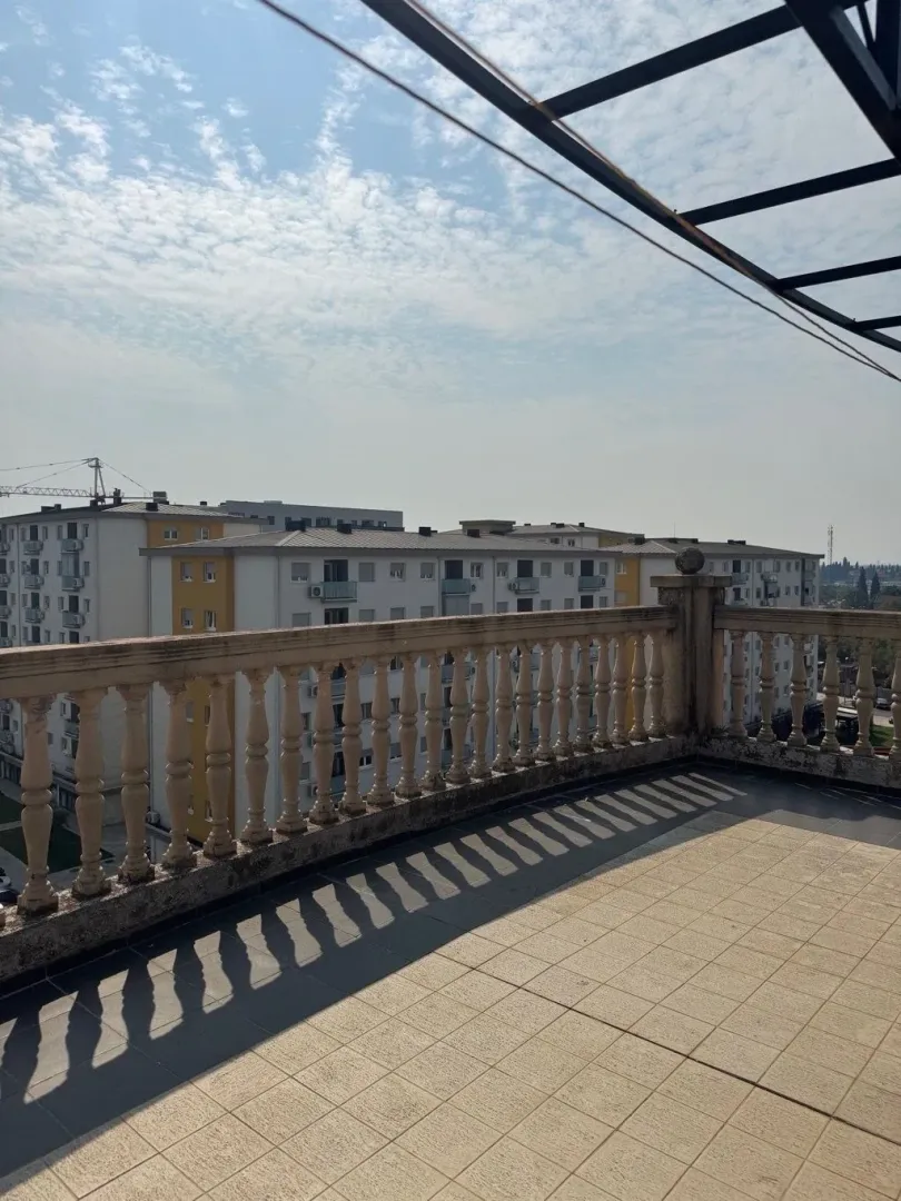 Spacious terrace with a stone railing and a view of surrounding buildings.