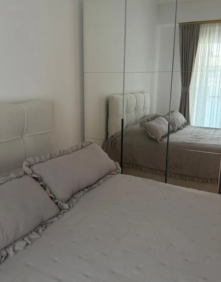 Pogled na bračni krevet u spavaćoj sobi sa velikim ogledalom na ormaru.