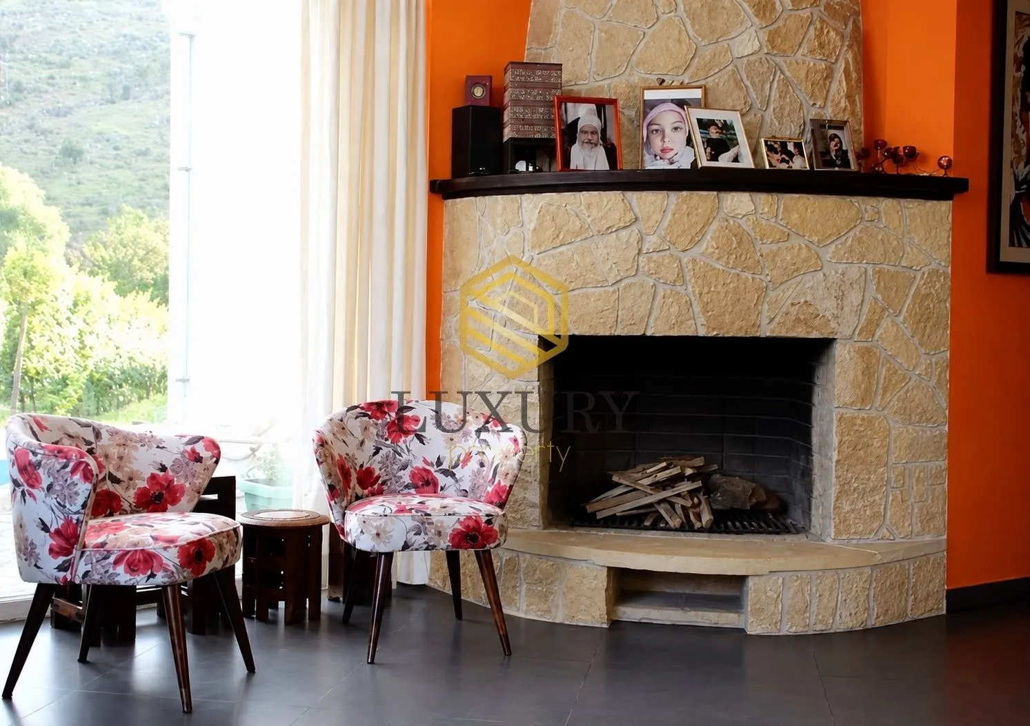 Living room with a stone fireplace and armchairs with floral pattern.