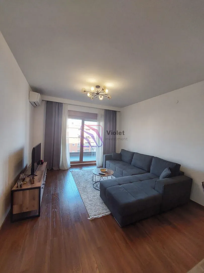 Living room with a sectional sofa, TV unit, and access to the terrace.