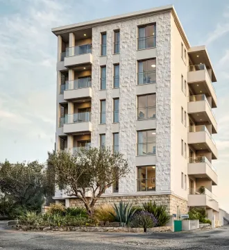 Exterior view of a modern residential building with balconies and a stone facade. - image 4