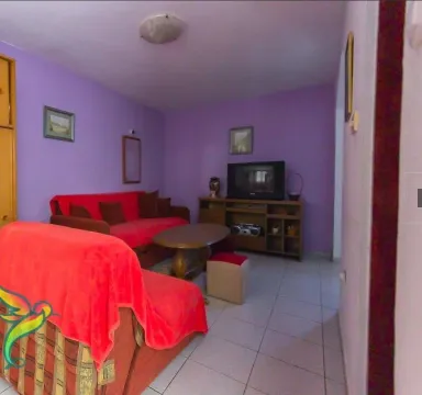 Dnevna soba sa ljubičastim zidovima, crvenim namještajem i televizorom. - image 14