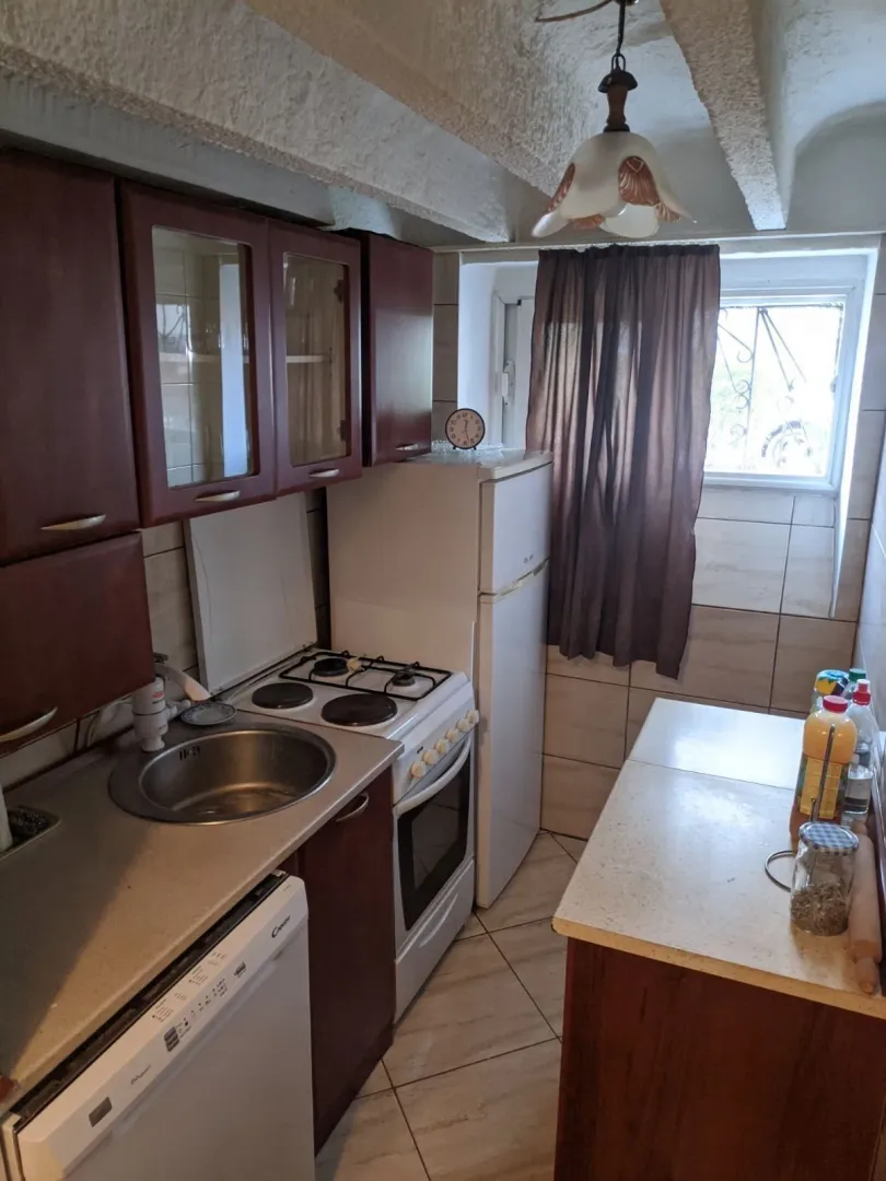Small functional kitchen with wooden cabinets and appliances.