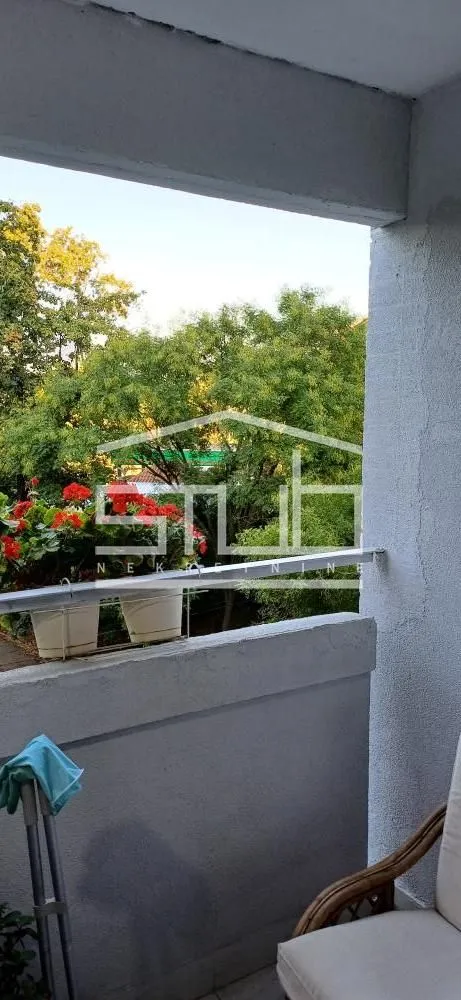 Manji balkon sa pogledom na drveće i cveće u saksijama.
