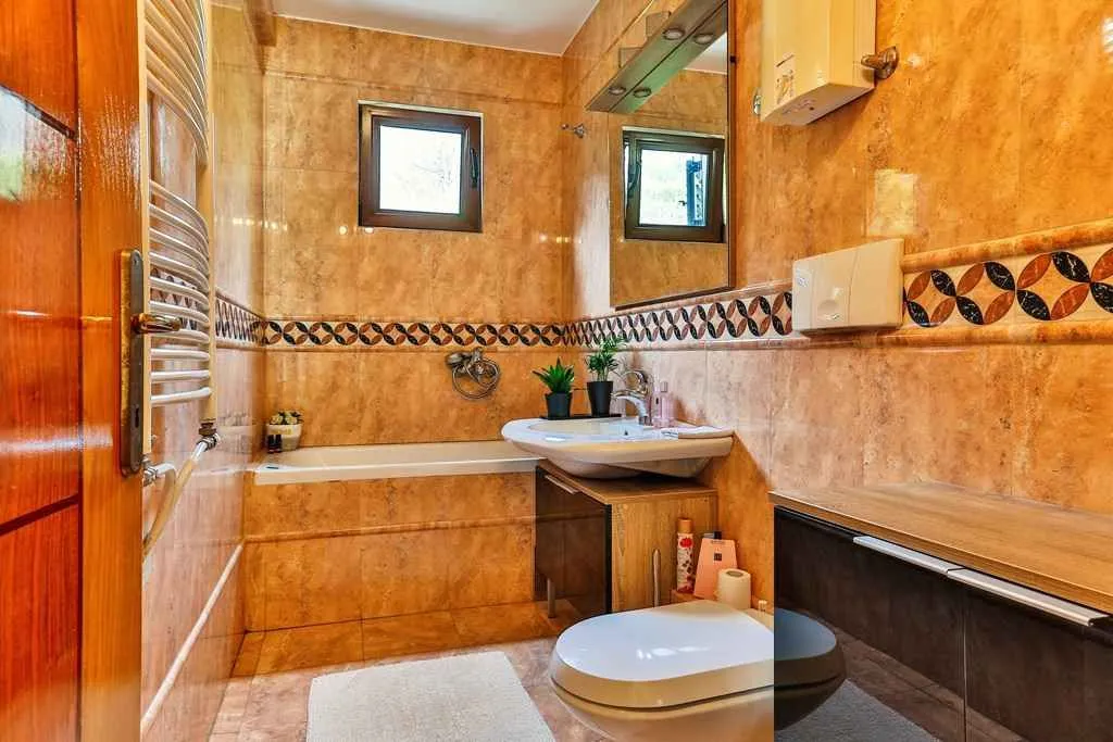 Bathroom with a bathtub, sink, and warm-toned ceramic tiles.