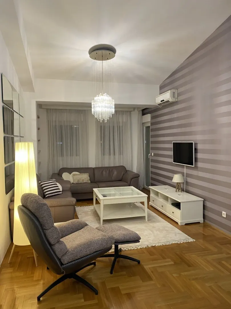 Bright living room with a leather sofa set, armchair, and TV stand.