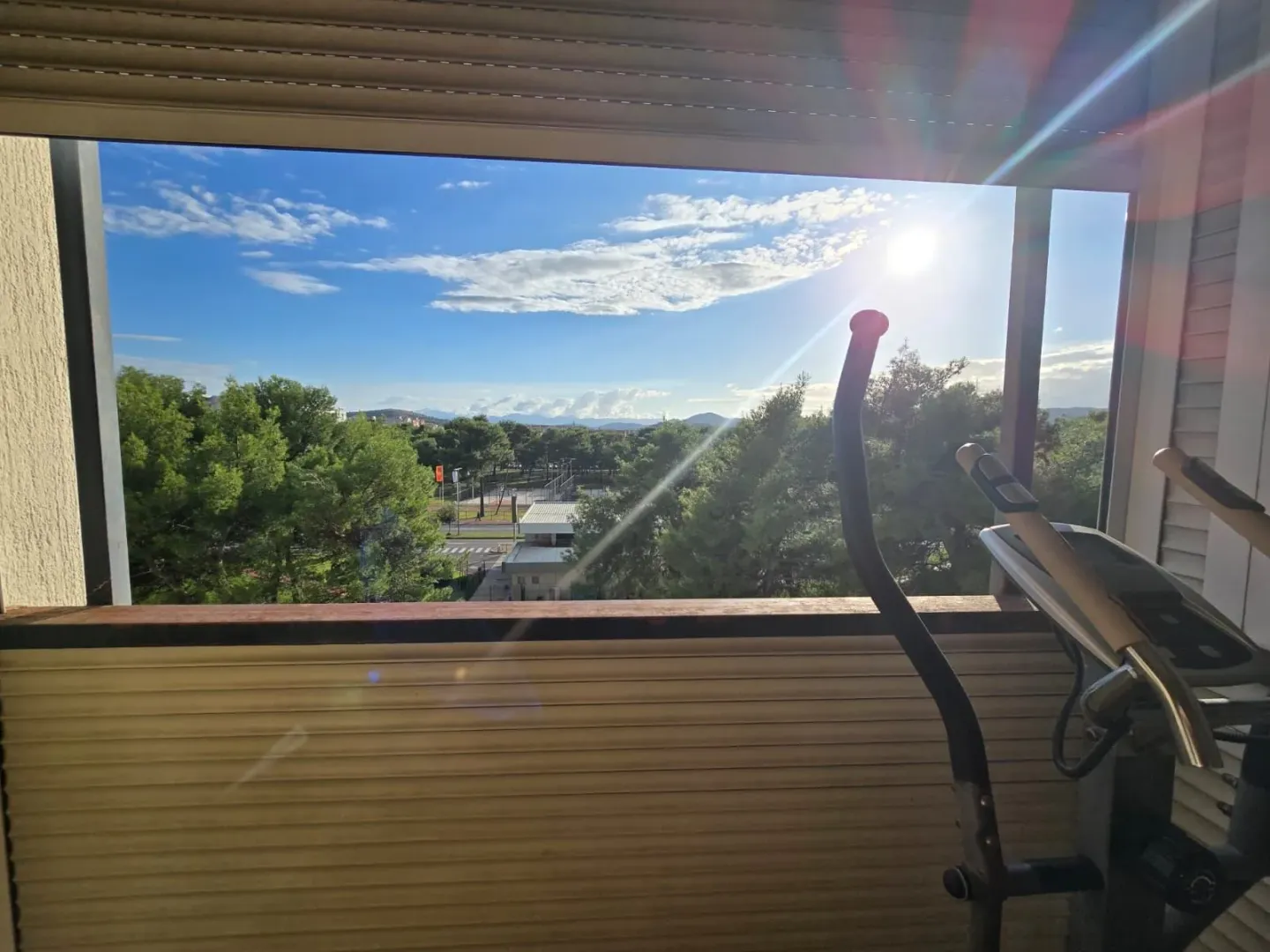 View from the enclosed balcony towards the surrounding greenery and city.