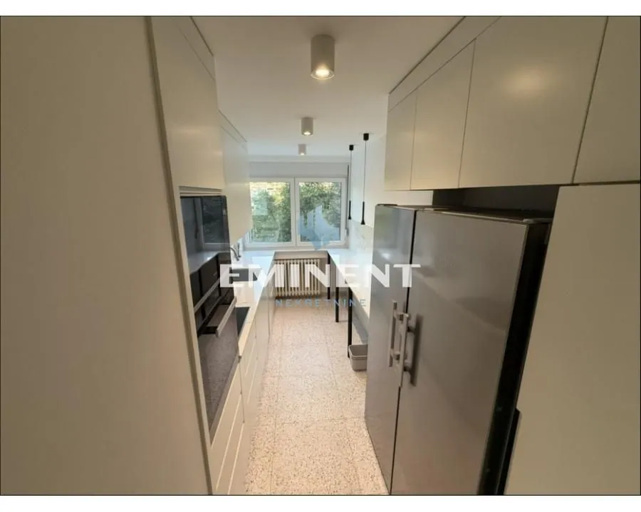 Narrow kitchen equipped with white cabinets and appliances.