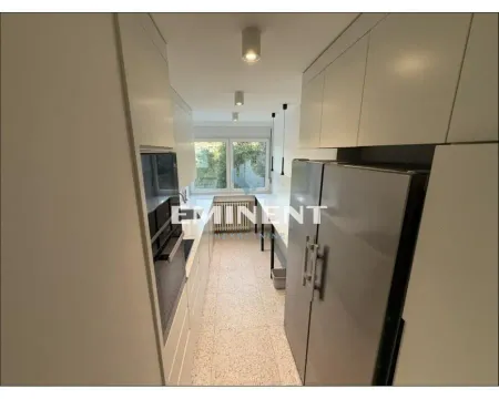 Narrow kitchen equipped with white cabinets and appliances. - image 5