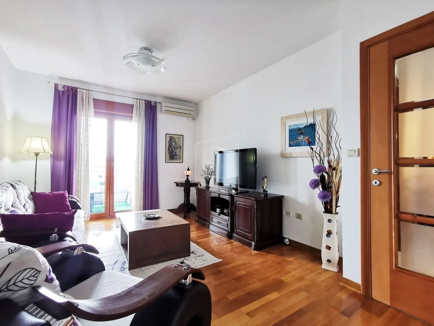 Bright living room with wooden furniture and balcony access.