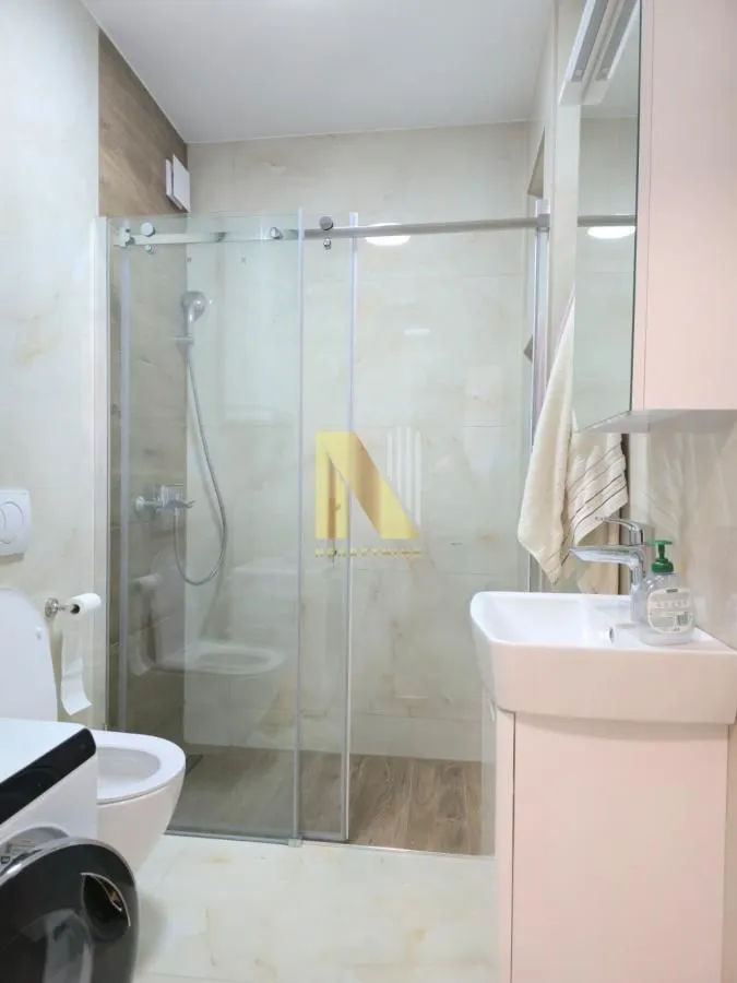 Moderno kupatilo sa tuš kabinom, umivaonikom i wc šoljom.
