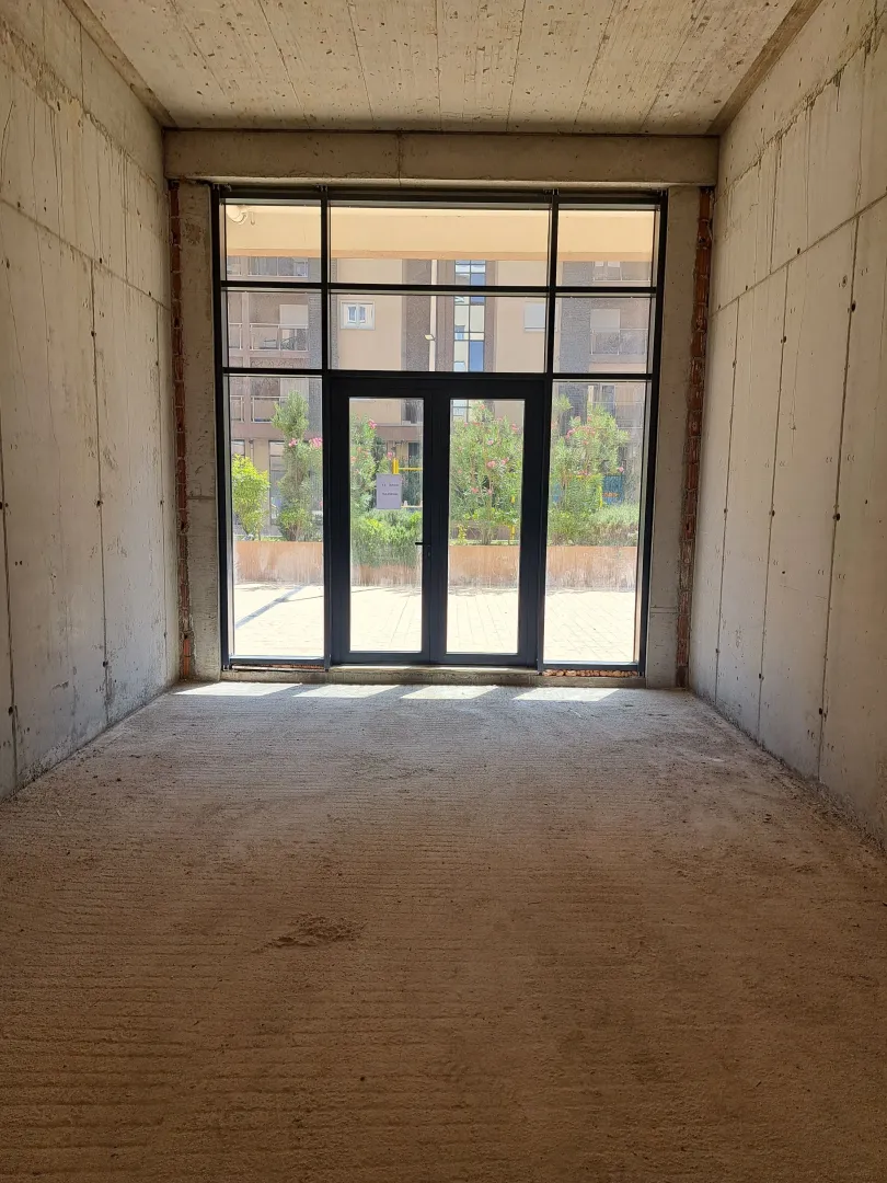Unfinished commercial space with glass entrance doors and a courtyard view.