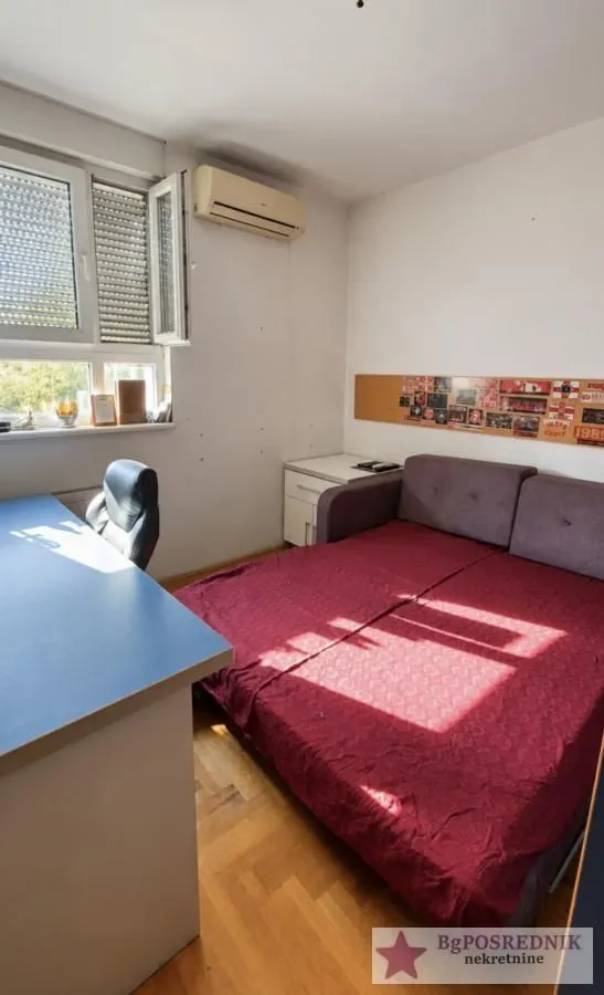 Smaller bedroom with a bed, desk, and air conditioning unit.