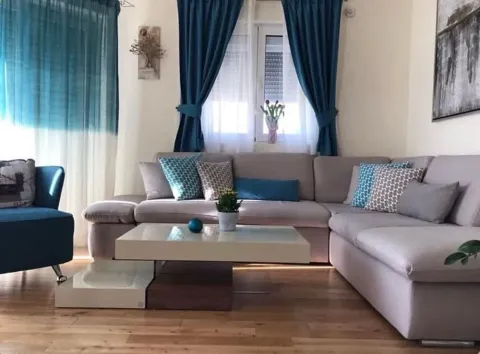 Living room with a sectional sofa, coffee table, and blue accents. - image 2