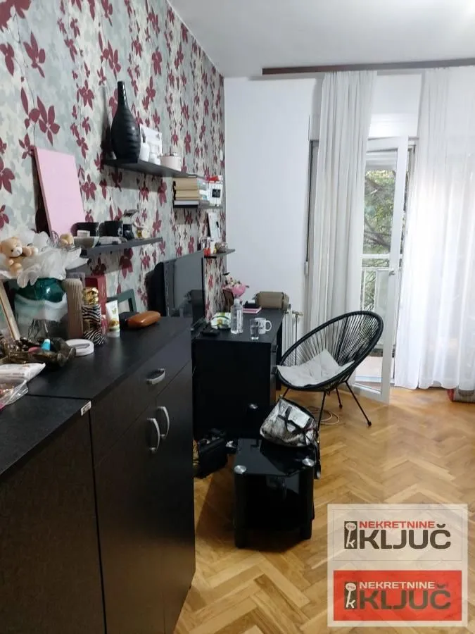 Dnevna soba sa nameštajem, radnim stolom i izlazom na terasu.