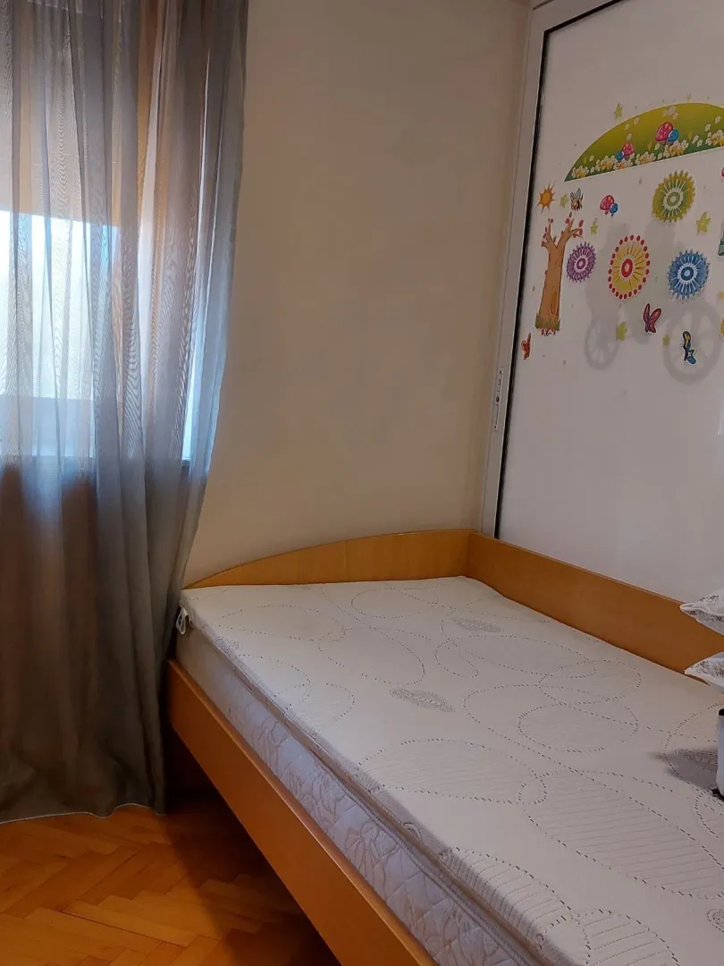 Dječija soba sa jednim krevetom pored prozora.