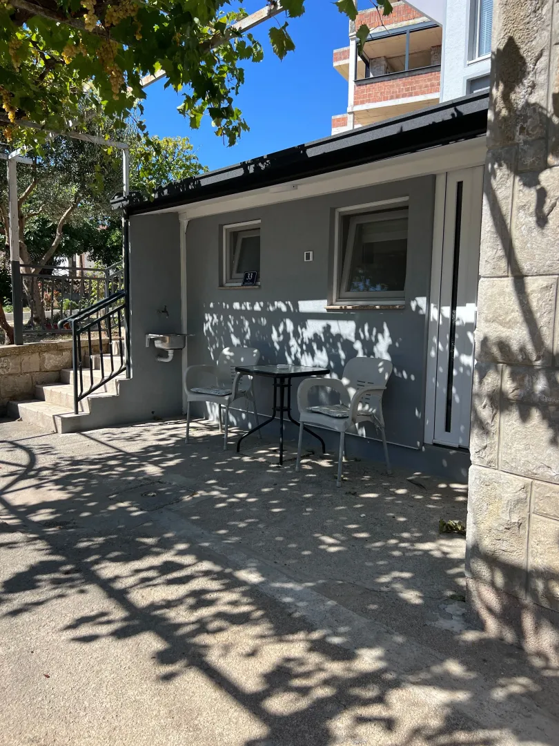 A paved courtyard with outdoor seating in front of the ground floor of the house.
