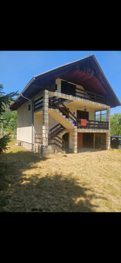 Pogled na spoljašnjost kuće sa spoljnim stepenicama i dvorištem.