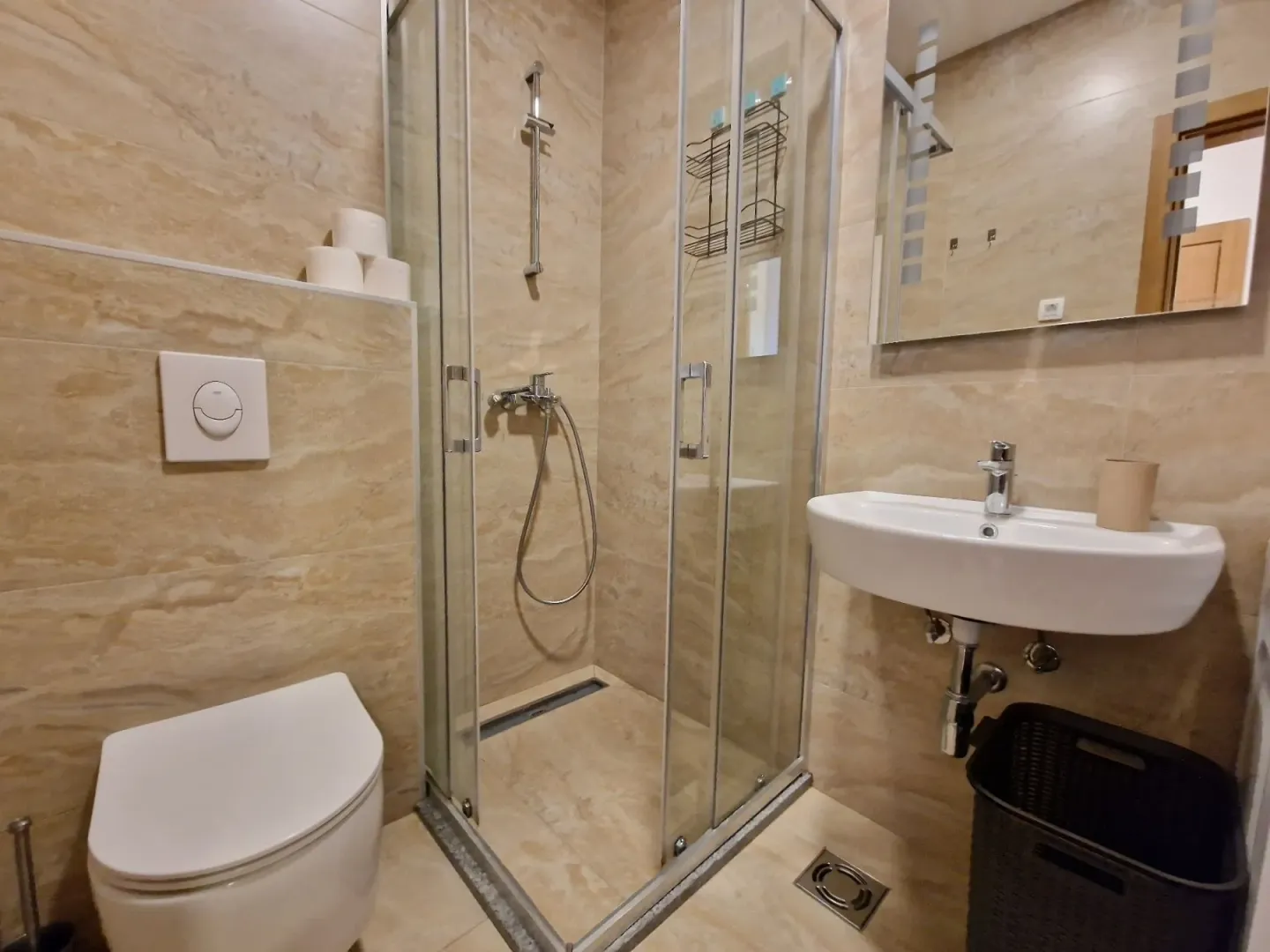 Kupatilo opremljeno tuš kabinom, umivaonikom i wc šoljom.