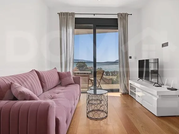 Living room with a pink sofa, television, and a sea view.