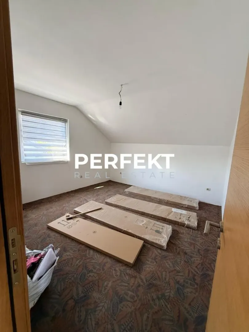 Prazna prostorija sa upakovanim nameštajem na podu i jednim prozorom.