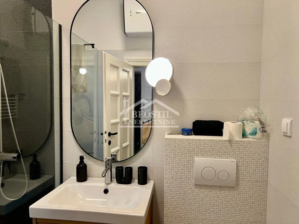 Modernly equipped bathroom with a sink, mirror, and walk-in shower.