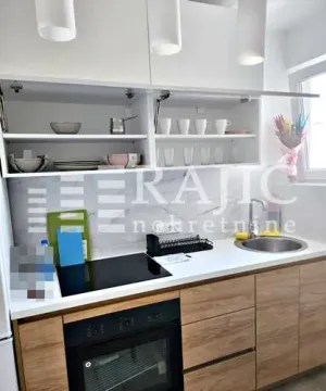 Modern kitchen with white cabinetry, wooden lower cabinets, and a built-in oven. - image 5