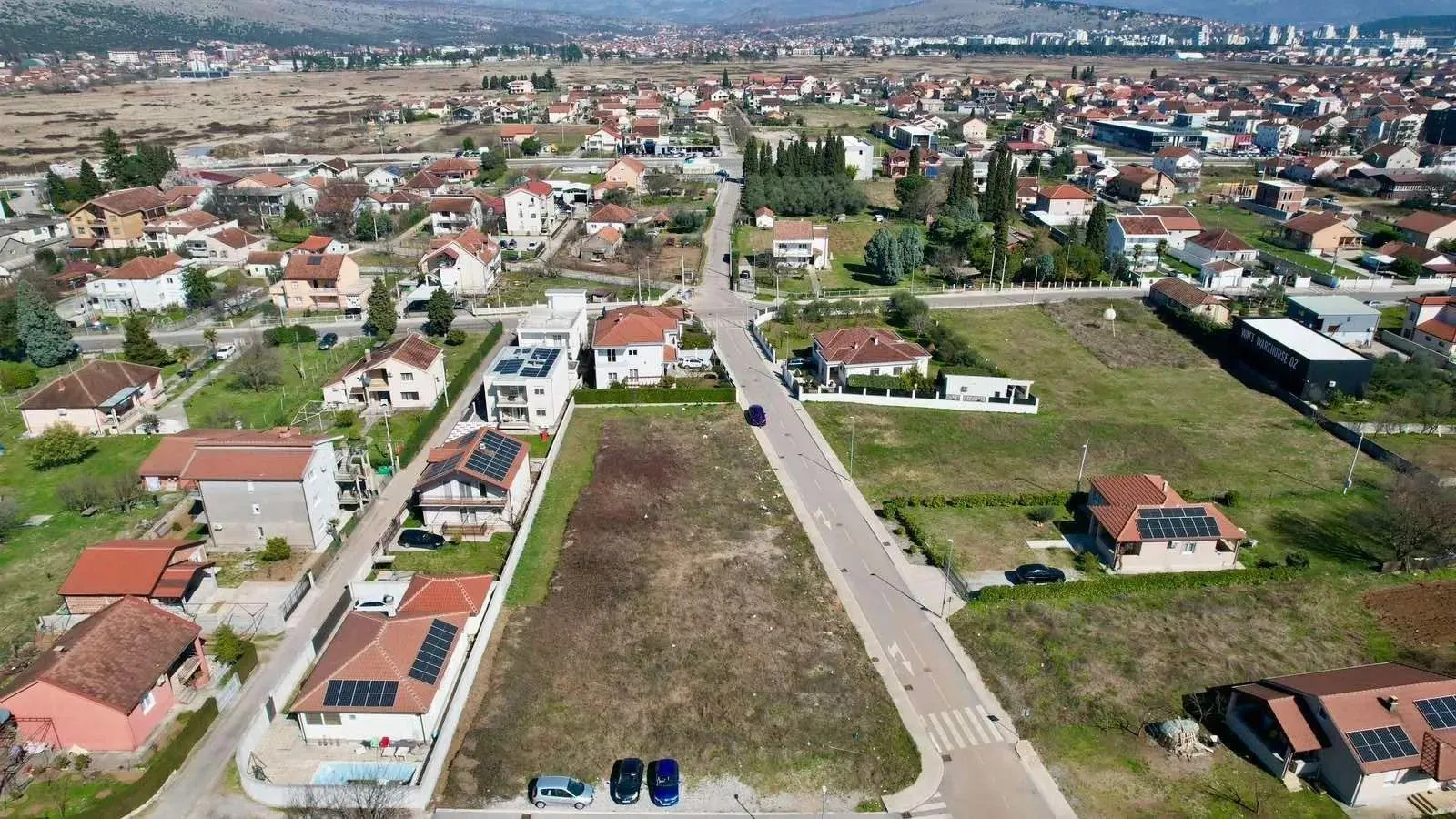 Pogled iz vazduha na građevinsku parcelu i okolno naselje.