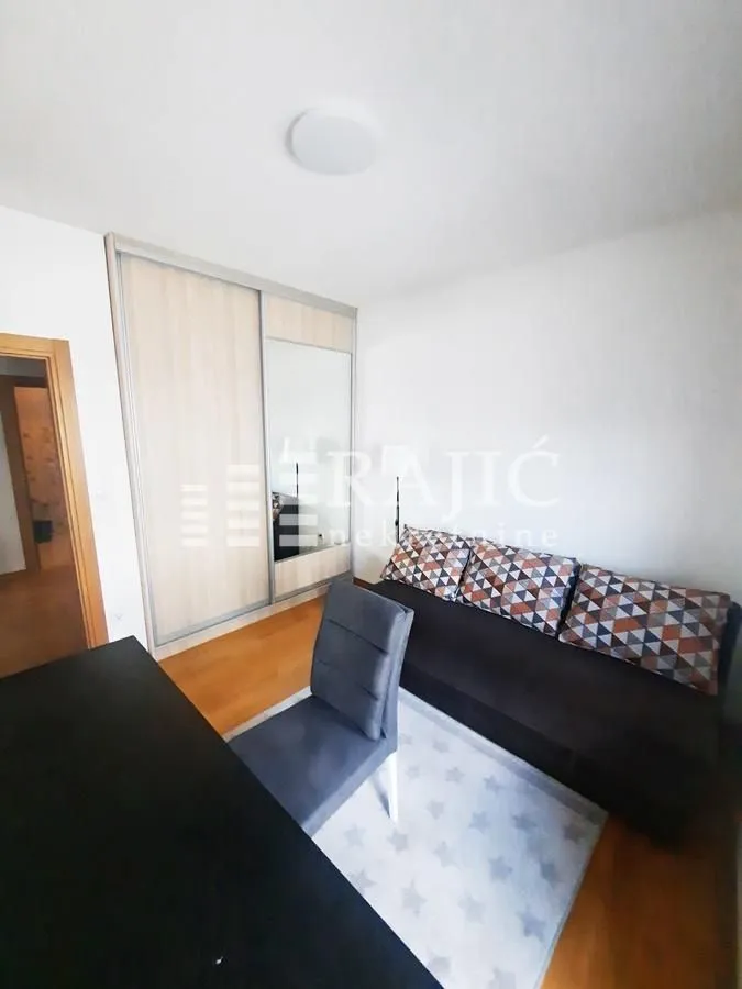 Small bedroom with a sofa bed, wardrobe, and desk.