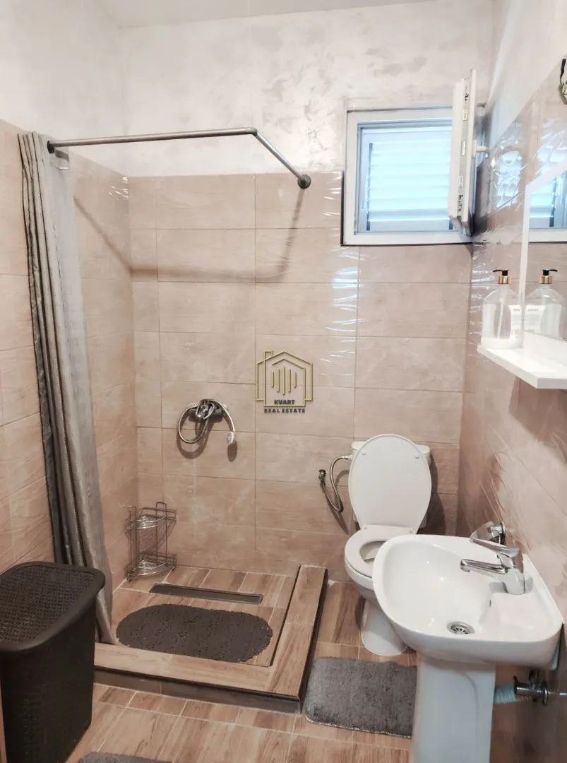 Smaller bathroom with a walk-in shower, washbasin, and toilet.