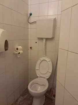 Small bathroom lined with white tiles featuring a toilet. - image 3