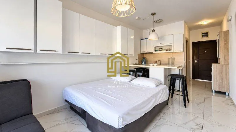 Studio apartment with a bed and a kitchen area in the same room.