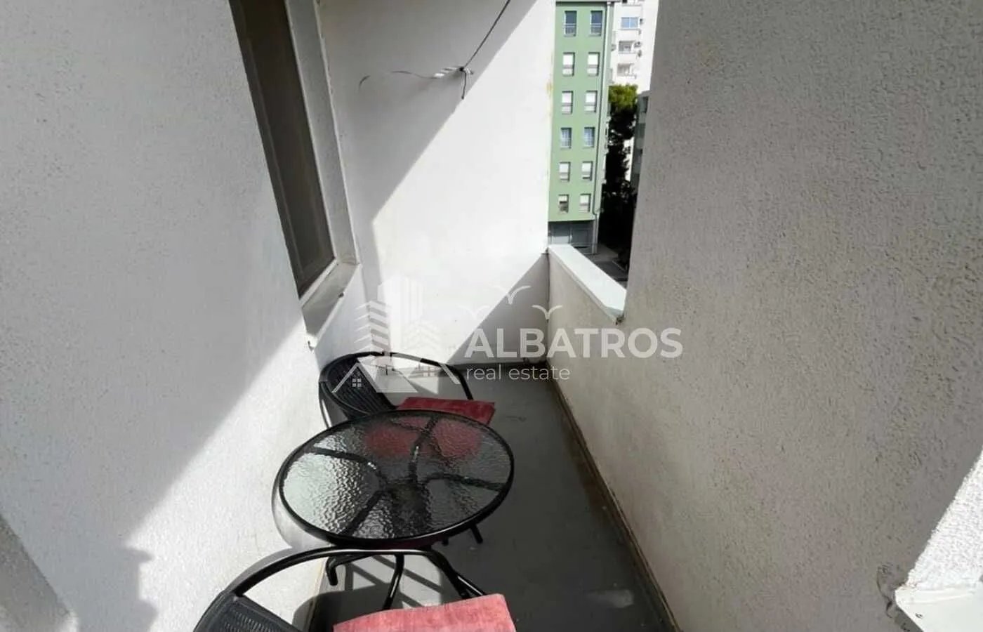 Manji balkon opremljen sa stolom i stolicama.