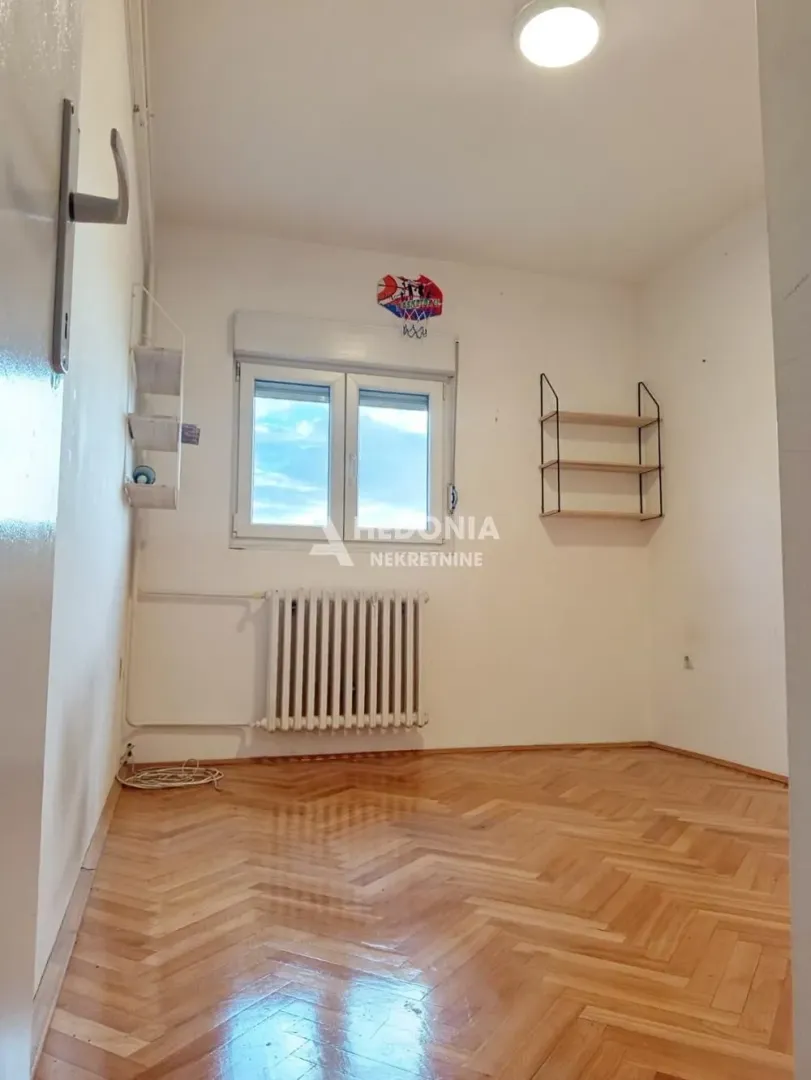 Empty room with parquet flooring and a window.