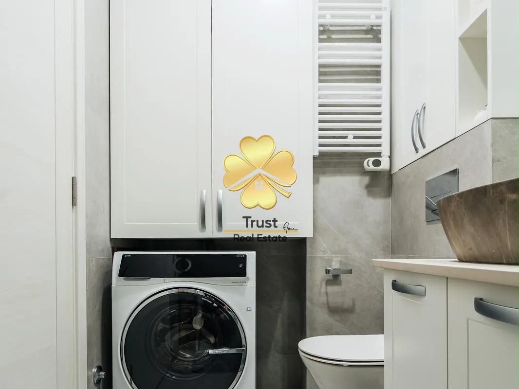 Moderne kupatilo sa bijelim elementima, veš mašinom i wc šoljom.