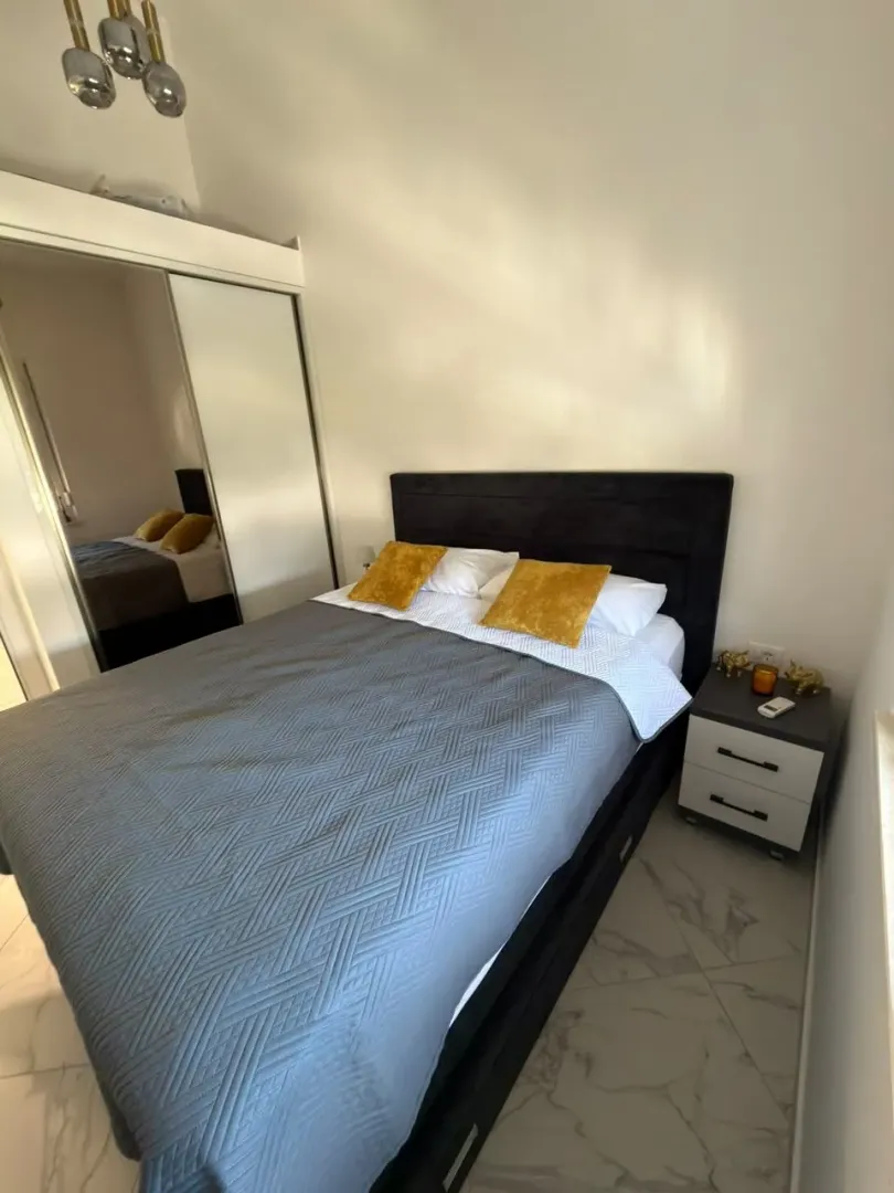 Furnished bedroom with a double bed and a mirrored built-in wardrobe.