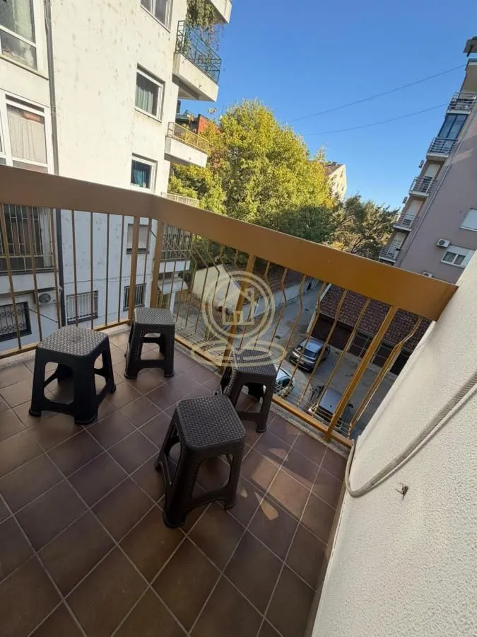 Manji popločani balkon sa ogradom i stolicama.