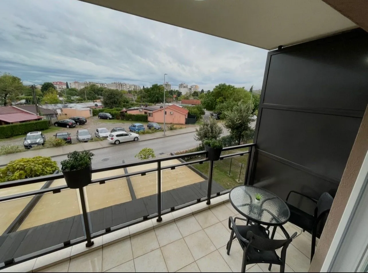 Natkriveni balkon sa garniturom za sedenje i pogledom na ulicu.