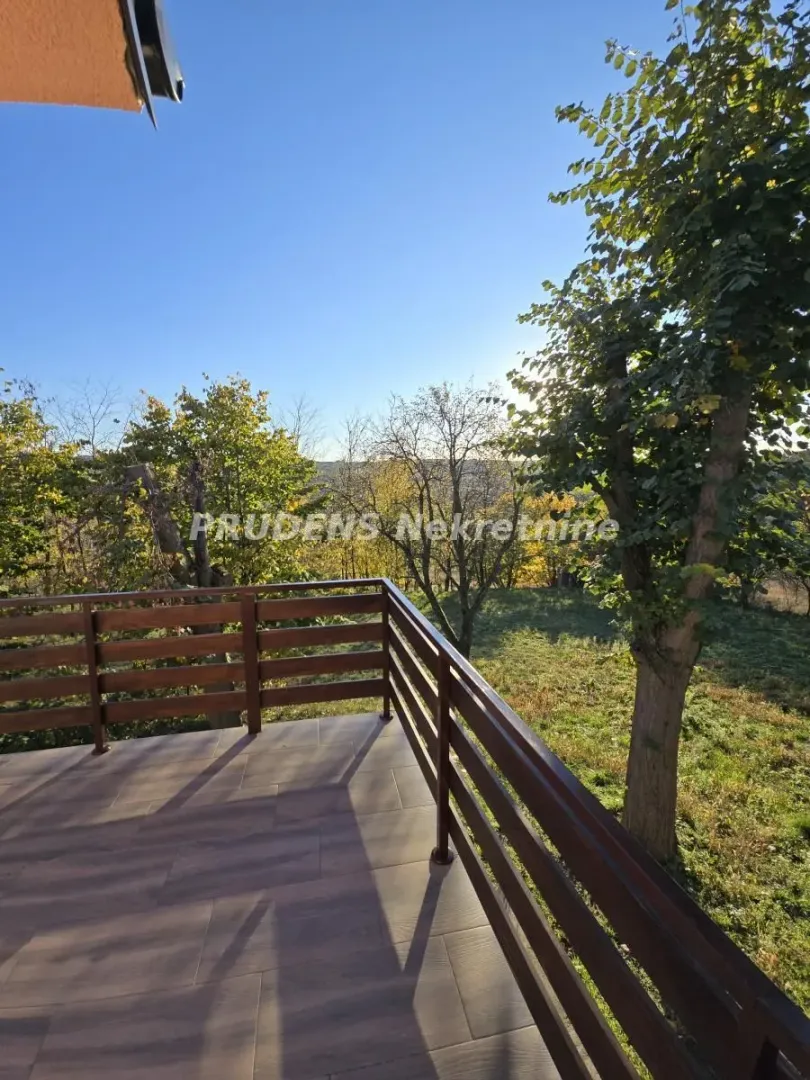 Tiled terrace with a wooden railing and a view of nature and trees.